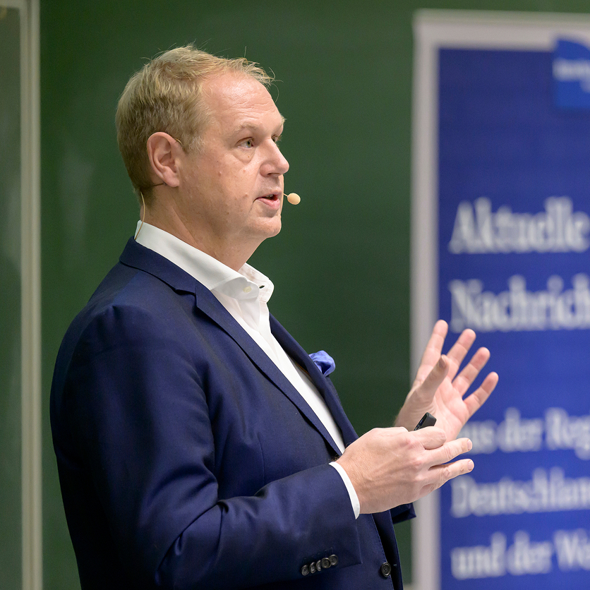Prof. Dr. Norbert Frey with a microphone during a lecture as part of the &ldquo;Medicine in the Evening&rdquo; series.