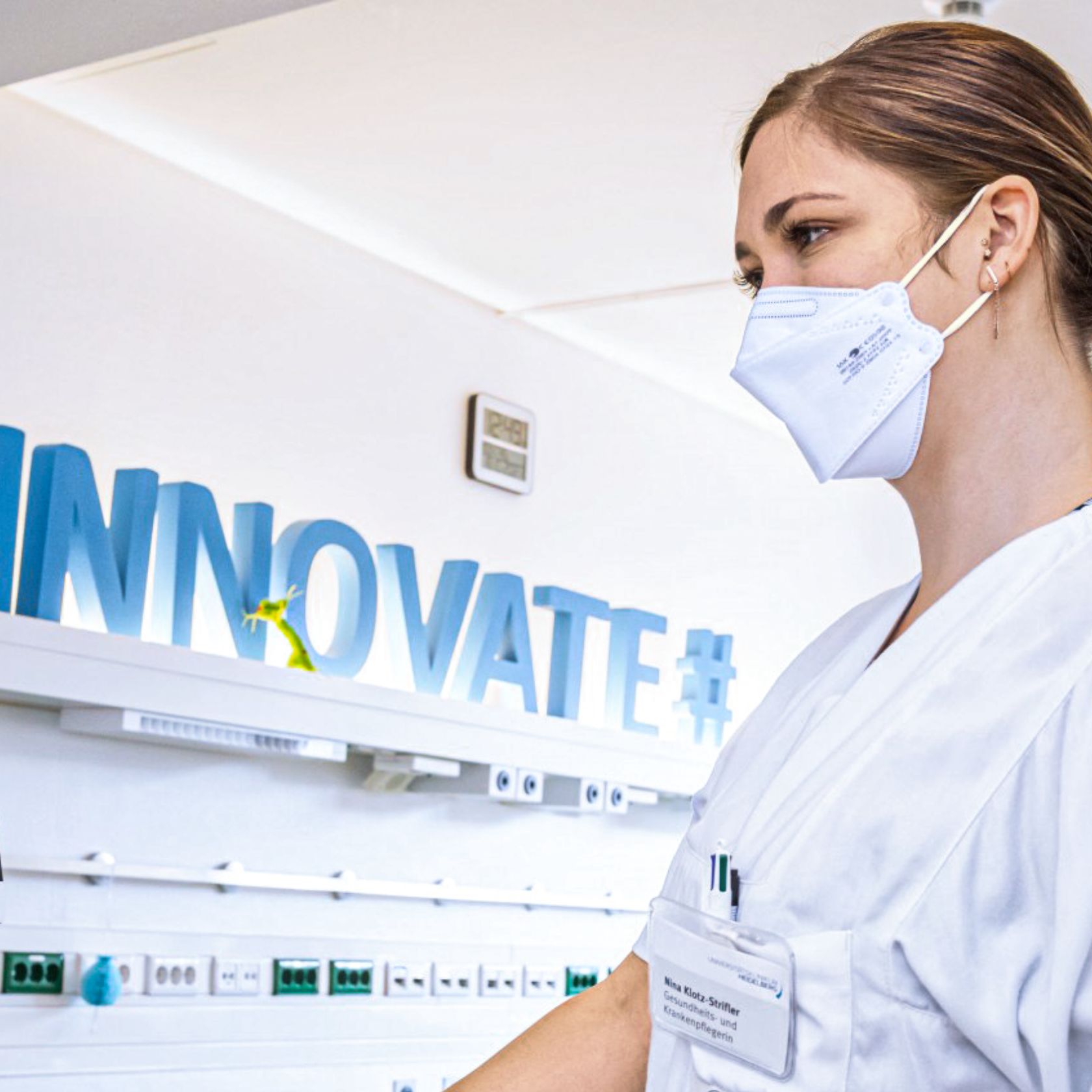 A young healthcare professional wearing a face mask, with the word &ldquo;Innovate#&rdquo; visible in the background.