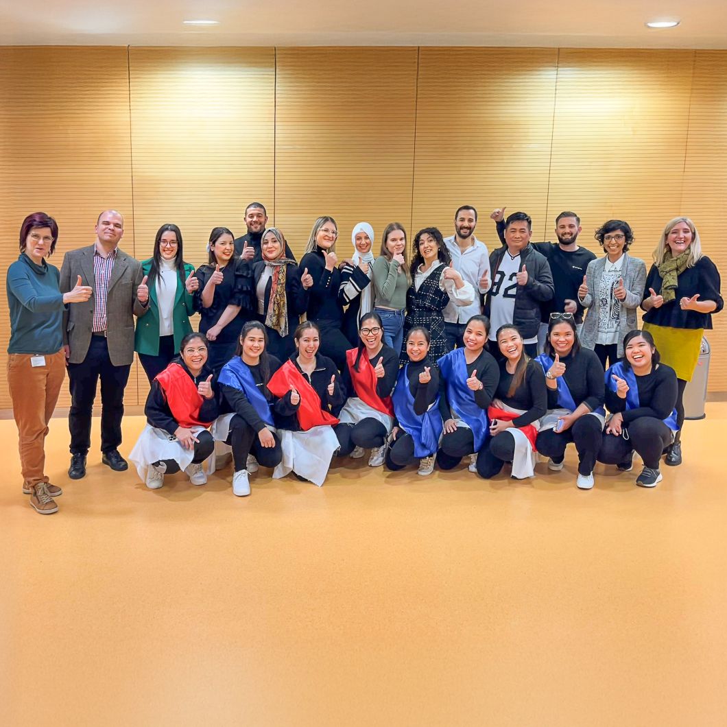 Group photo of new international nurses at Heidelberg University Hospital. The individuals are standing next to each other, smiling.