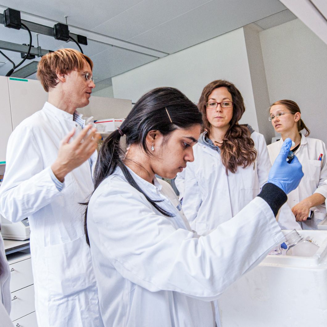 Medical students in white coats practise practical skills in the laboratory.