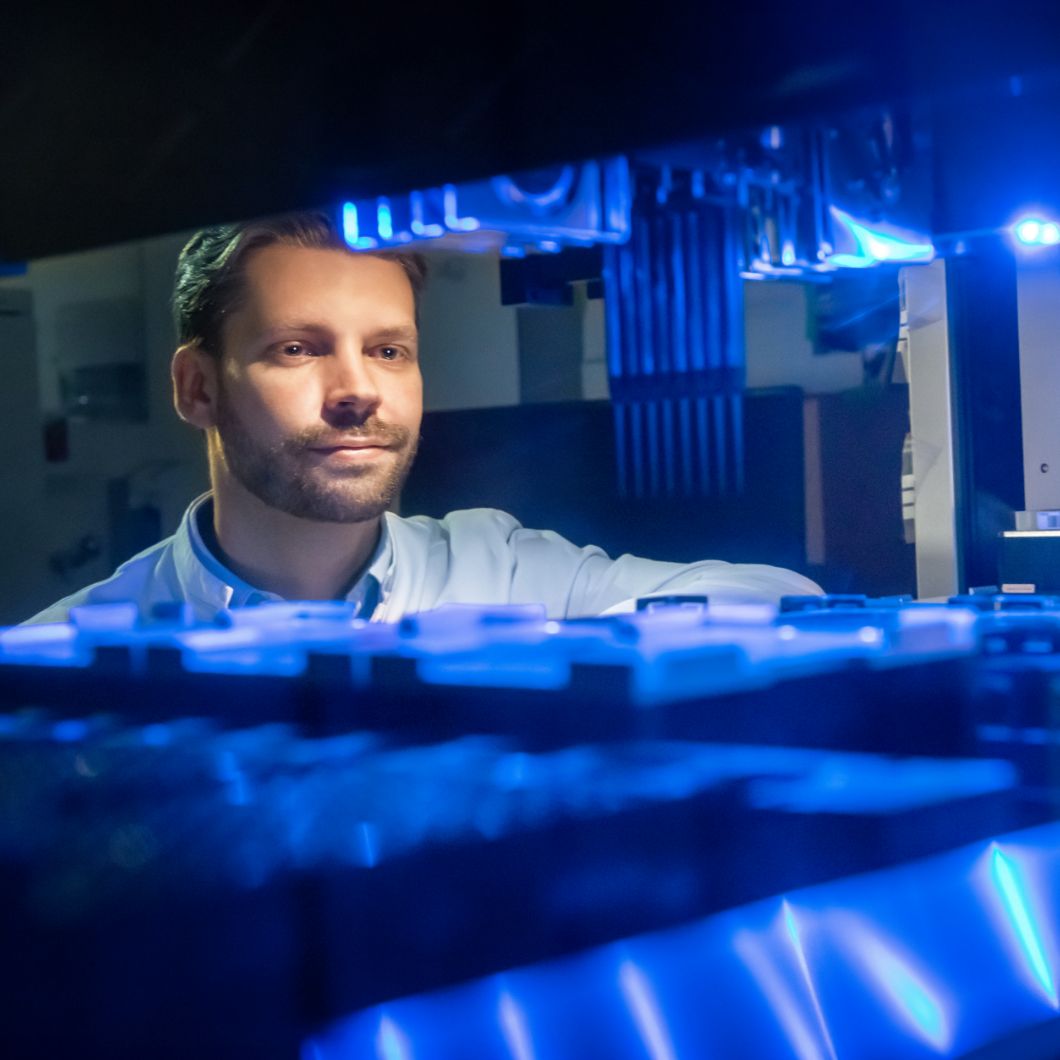 Virtual dissection table with a representation of a body at muscle and bone level, next to it an anatomical teaching doll. In the background, shelves with scientific journals.