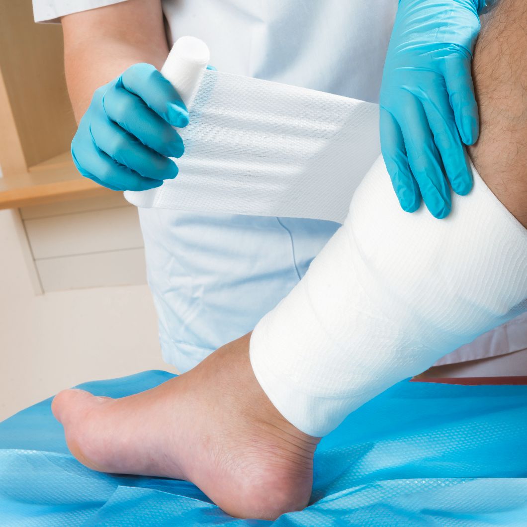 Hands applying a bandage to a lower leg.